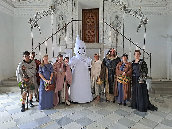 Besucher mit dem Maskottchen der Riegersburg im weißen Saal.