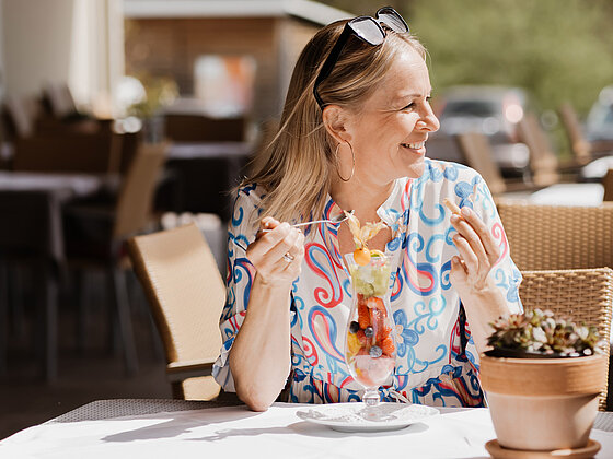 Dame sitzt in der Sonne im Restaurant Weitblick im Hotel das Eisenberg.