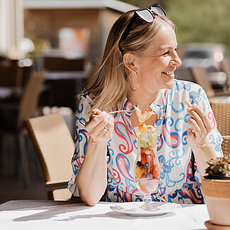 Dame sitzt in der Sonne im Restaurant Weitblick im Hotel das Eisenberg.
