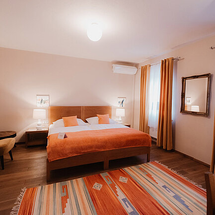 Doppelbett mit Sessel im Landhaus Doppelzimmer Lavendel ohne Balkon im Hotel das Eisenberg.