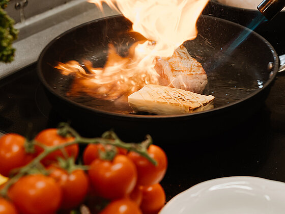 Essen wird in der Pfanne mit Feuer im Hotel das Eisenberg zubereitet.