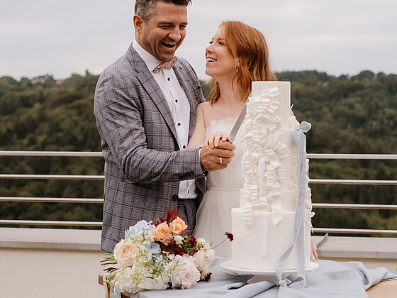 Brautpaar schneidet die Hochzeitstorte im Freien beim Hotel das Eisenberg an.