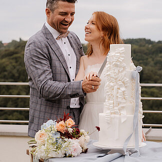 Brautpaar schneidet die Hochzeitstorte im Freien beim Hotel das Eisenberg an.