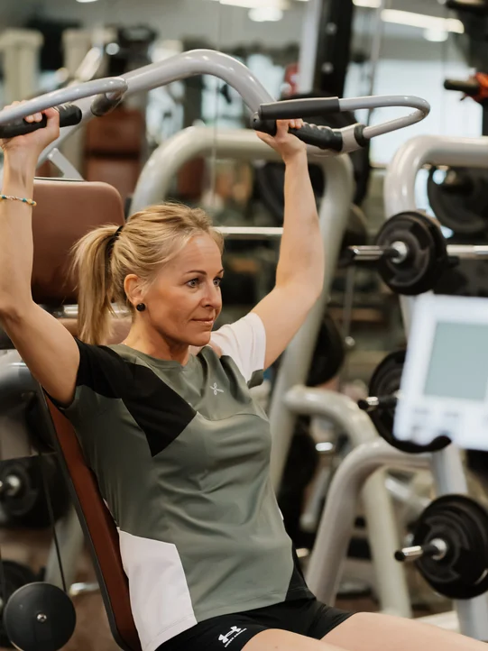 Dame trainiert ihre Arme im Fitnessraum vom Hotel das Eisenberg.