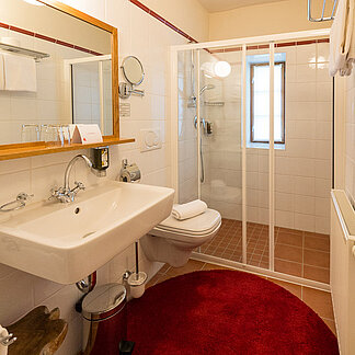 Badezimmer mit Dusche und Waschbecken in Zimmer Vergissmeinnicht im Landhaus vom Hotel das Eisenberg  (c) Jean Van Luelik Photographer.