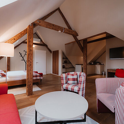 Sitzbereich mit Couch, Sesseln und Tisch im Zimmer Vergissmeinnicht im Landhaus vom Hotel das Eisenberg.