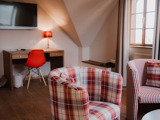 Sitzecke mit Sesseln, Schreibtisch und Fernseher im Zimmer Vergissmeinnicht im Landhaus beim Hotel das Eisenberg.