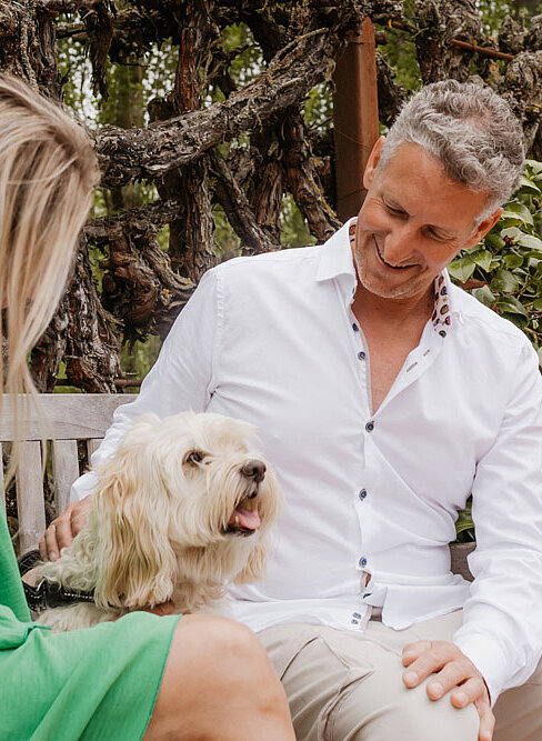Dame und Herr sitzen mit Hund in der Gartenanlage vom Hotel das Eisenberg. Dame und Herr sitzen mit Hund in der Gartenanlage vom Hotel das Eisenberg.