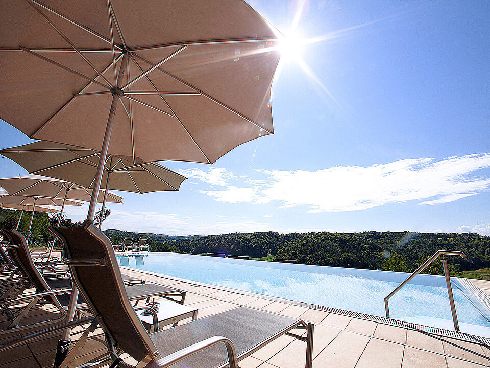 Außenpool mit Liegen und Sonnenschirmen beim Hotel das Eisenberg.