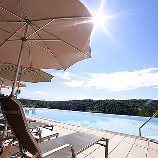 Außenpool mit Liegen und Sonnenschirmen beim Hotel das Eisenberg.