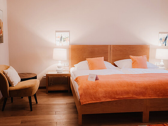 Doppelbett mit Sessel im Landhaus Doppelzimmer Lavendel ohne Balkon im Hotel das Eisenberg.
